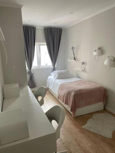 a white bedroom with a bed and a table at Dafundo Family Flat in Cruz Quebrada