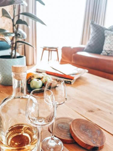 a bottle of wine and two glasses on a table at De Kombuys in Oudtshoorn