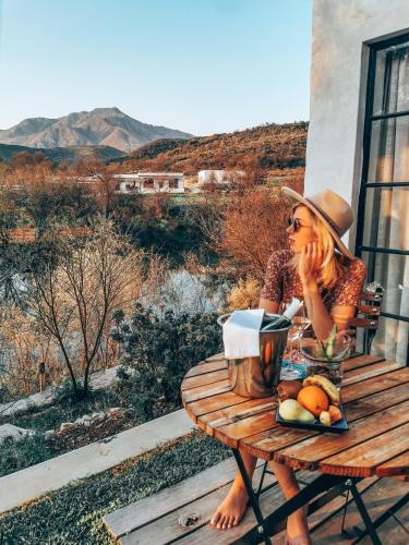 a woman sitting at a picnic table with a basket of fruit at De Kombuys in Oudtshoorn