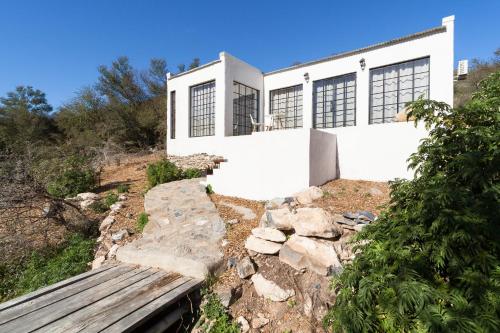 a white house with a bench in front of it at De Kombuys in Oudtshoorn