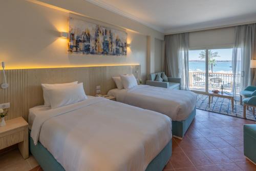 two beds in a hotel room with a view of the ocean at Safir Marsa Matrouh Resort in Marsa Matruh