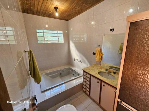 a bathroom with a tub and a sink at Chácara Belvedere.Espaço rural, descanso e lazer in Londrina