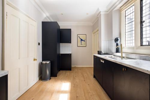 una cucina con armadi neri e una porta bianca di The Woking Wonder - Captivating 3BDR Flat with Parking a Woking