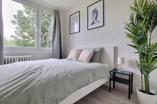 a white bedroom with a bed and a potted plant at Finnem Rentals Varnsdorfská in Prague