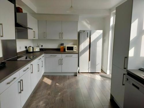 a kitchen with white cabinets and a refrigerator at Wentworth Road Accomodation in Doncaster