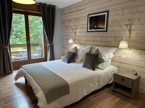 1 dormitorio con 1 cama grande y pared de madera en Coté Forêt en Orbey