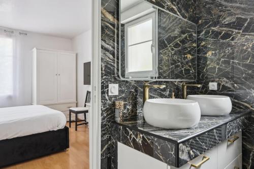 a black and white bathroom with two sinks and a bed at Résidence élégance Disneyland in Serris