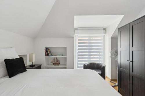 een slaapkamer met een groot wit bed en een stoel bij Résidence élégance Disneyland in Serris