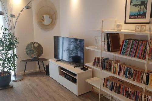 uma sala de estar com televisão e prateleiras de livros em Appartement 80m2 6 couchages em Garidech