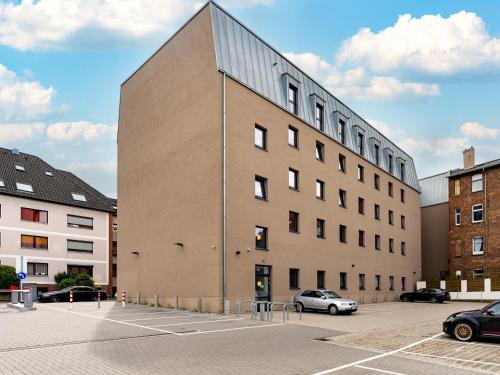 ein großes Gebäude mit Autos auf einem Parkplatz in der Unterkunft B&B Hotel Hildesheim in Hildesheim