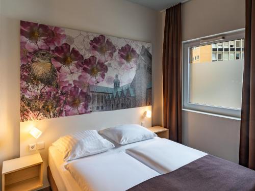 1 dormitorio con 1 cama y una pintura en la pared en B&B Hotel Hildesheim, en Hildesheim