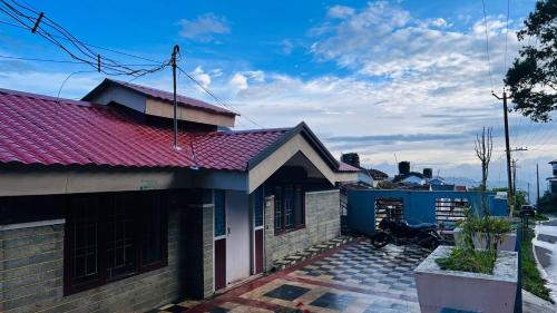 a house with a red roof on a patio at Mountain View cottage in Ooty