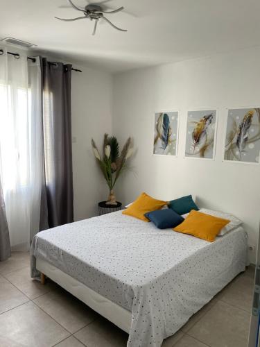 1 dormitorio con 1 cama con almohadas amarillas y azules en Chambre avec salle de bain privée dans villa, en Manosque