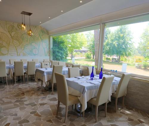 una sala da pranzo con tavoli, sedie e una grande finestra di Hotel Hiki a Bibione