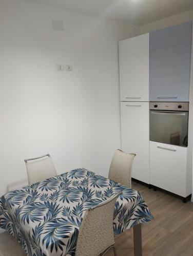 uma cozinha com uma mesa, 2 cadeiras e um frigorífico em Alloggio Via Bertini em Firenzuola