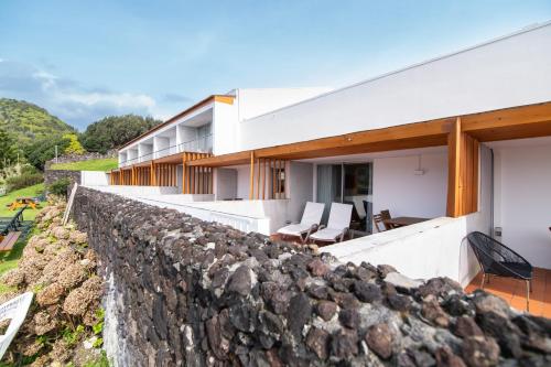 a house on a hill with a stone wall at ANC Resort in Caloura