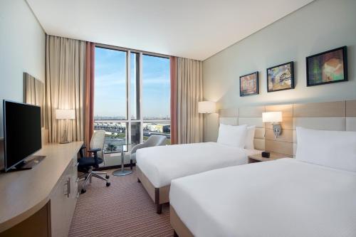 um quarto de hotel com duas camas e uma secretária com uma televisão em Hilton Garden Inn Al Khobar em Al Khobar