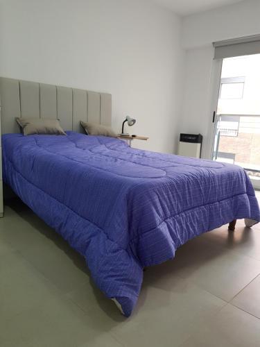 1 cama con edredón morado en un dormitorio en Departamento, Excelente calidad y Ubicación, a estrenar en Rosario
