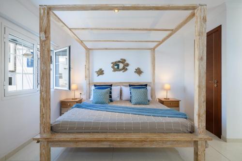 a bedroom with a wooden canopy bed with blue pillows at Ocean Pebbles, The Sound of the Sea in Punta de Mujeres