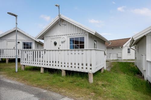 a white house with a porch on the side of a street at Tanumstrand SPA & Resort Stugor in Grebbestad