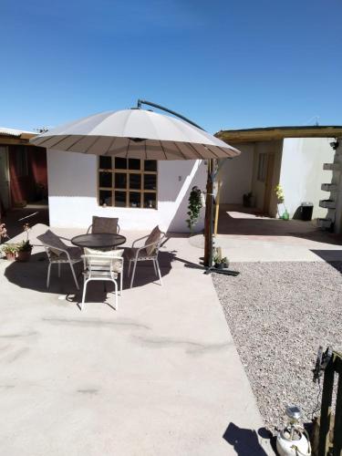 un patio con mesa, sillas y sombrilla en Casa Dorada en San Pedro de Atacama