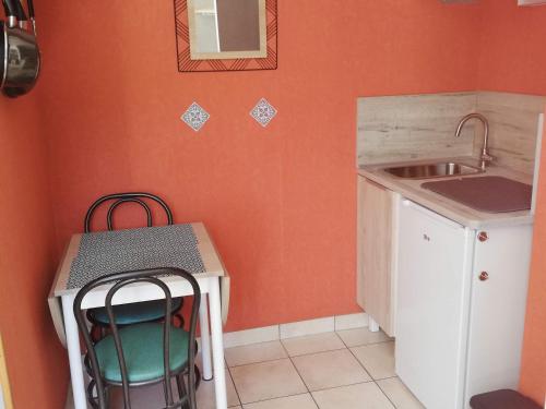 una pequeña cocina con fregadero, mesa y sillas en CHAMBRE STUDIO avec KICHENETTE SOLEIL DE NACRE, en Hermanville-sur-Mer