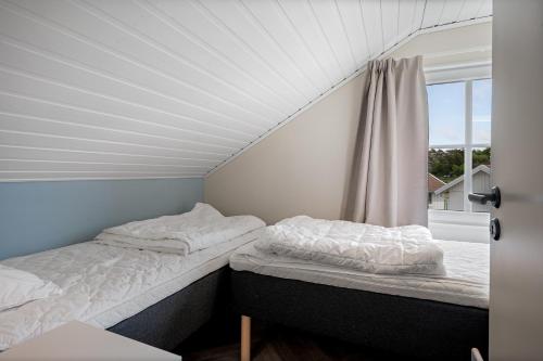 two beds in a room with a window at Tanumstrand SPA & Resort Stugor in Grebbestad