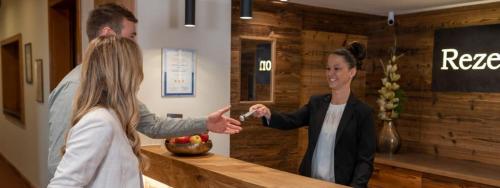 a woman feeding a man a bowl of fruit at Hotel-Gasthof Weisses Ross in Schwaig bei Nürnberg
