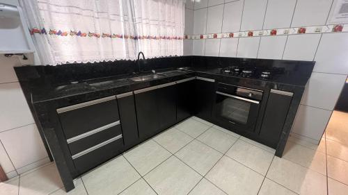 una cocina con armarios negros y fregadero en RANCHO KWILL en Serra Negra