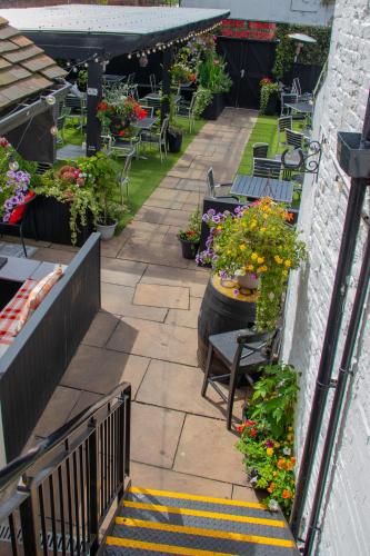 an outdoor patio with tables and chairs and flowers at Rose & Crown Rooms in Beverley