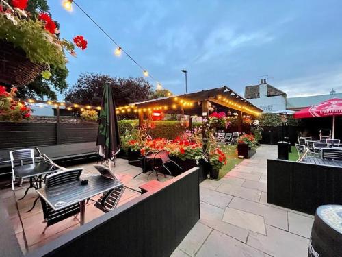 een patio met tafels en stoelen en een parasol bij Rose & Crown Rooms in Beverley