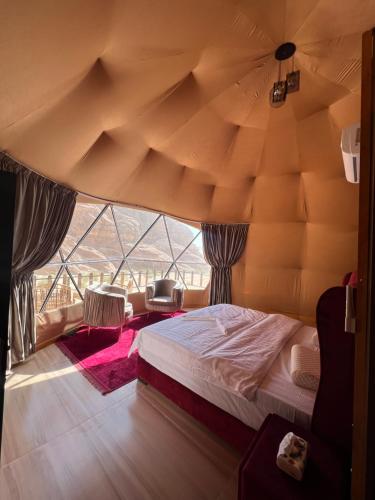 a bedroom with a bed and a large window at Wadi Rum Mars Camp in Wadi Rum