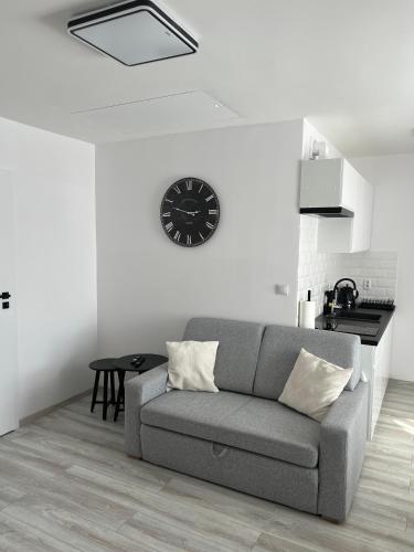 a living room with a couch and a clock on the wall at Apartamenty Przy Deptaku in Świnoujście