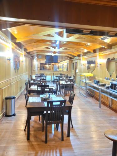 un restaurant avec des tables et des chaises en bois et une cuisine dans l'établissement Hostal Balmaceda, à Punta Arenas