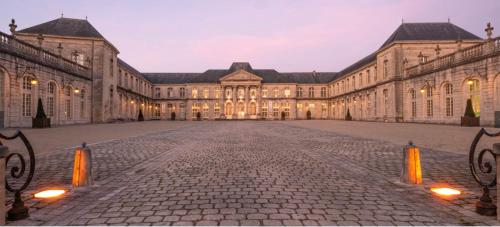 un grand bâtiment avec une cour en pierre au crépuscule dans l'établissement La chambre de Madeleine, à Commercy