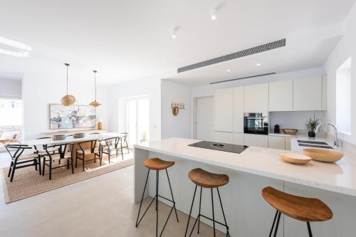 a kitchen with white cabinets and a large island with bar stools at Exclusive Luxury Moca beachfront villa, Molos, Paros in Molos Parou