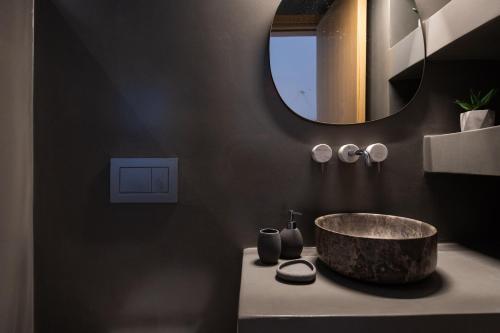 Exclusive Luxury Moca beachfront villa, Molos, Paros في Molos Parou: حمام مع حوض حجري ومرآة
