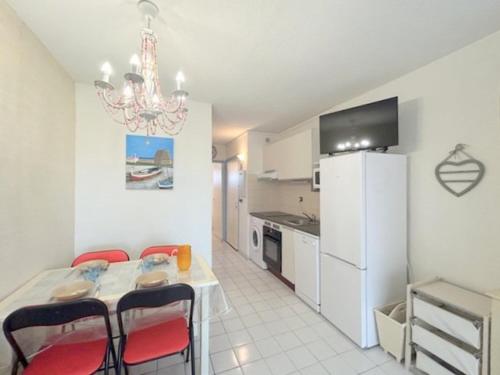 une cuisine avec une table, des chaises et un réfrigérateur dans l'établissement Appartement T2 situé proche de la mer terrasse parking privé 4POPL8, au Barcarès