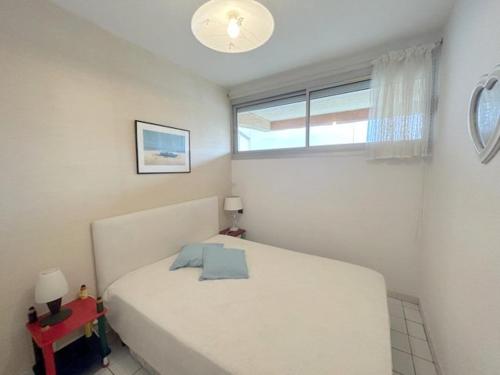 une chambre avec un lit blanc et une fenêtre dans l'établissement Appartement T2 situé proche de la mer terrasse parking privé 4POPL8, au Barcarès