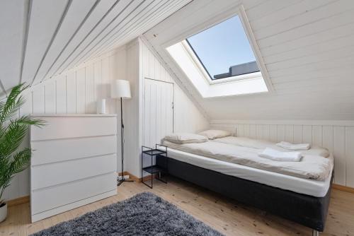 1 dormitorio en el ático con cama y ventana en Ny og sentral leilighet, en Kristiansand