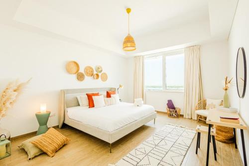 a white bedroom with a bed and a window at Voyage 2 Bedroom In Mayan With Ocean Views in Abu Dhabi