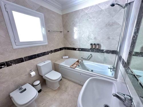 ein Badezimmer mit einer Badewanne, einem WC und einem Waschbecken in der Unterkunft Luxury Villa Ifara Private Heated Pool in Adeje