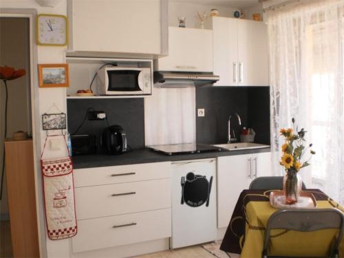 une petite cuisine avec des armoires blanches et un micro-ondes dans l'établissement Spacieux Studio - 100 m de la plage -Parking- vue mer 4PP1/35, au Barcarès