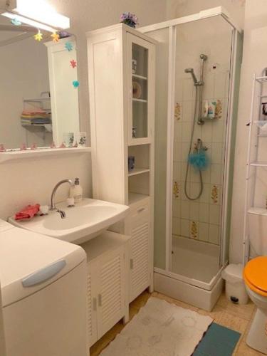 une salle de bain blanche avec une douche et un lavabo dans l'établissement Spacieux Studio - 100 m de la plage -Parking- vue mer 4PP1/35, au Barcarès