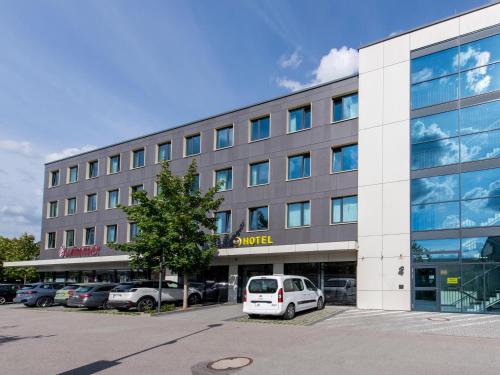 un edificio con un coche blanco aparcado delante de él en B&B Hotel München-Olympiapark, en Múnich