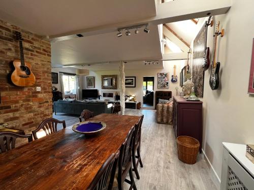 a dining room and living room with a wooden table at Eclectic Barn - Pergola & Dog-Friendly Garden in Calne
