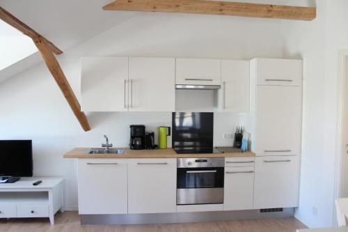 a kitchen with white cabinets and a stove at Kærskovgård ferielejligheder in Faxe