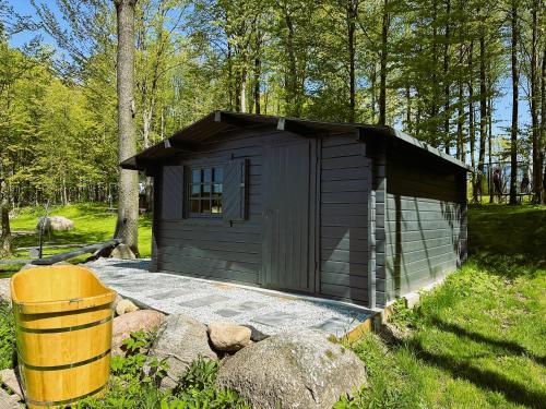 a small shed in a yard with a barrel at Wyspa Ciernie - Dom nad jeziorem z sauną i jacuzzi in Ciernie