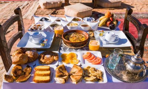 a table full of breakfast foods and orange juice at Holiday Desert Camp in Merzouga