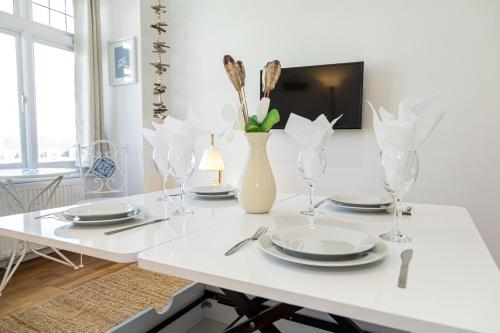 a white dining room table with plates and a vase with flowers at Ocean Breeze - 1 MINUTE FROM THE BEACH - 10 MINUTE FROM BIC - FAST WI-FI - SMART TV in Bournemouth